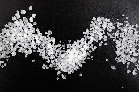 White rock salt scattered on black ceramic texture, soft focus