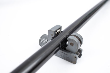 Pipe cutting tool on a black coated pipe, isolated on white background, soft focusの写真素材