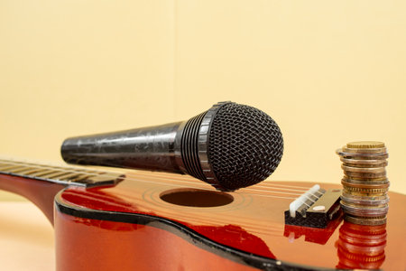 Microphone on ukulele strings, and a stack of coins, music revenue concept, soft focus