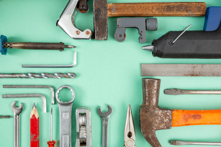 Multiple hand tools arranged on green background, with empty square copy space