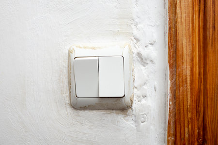 Dirty light switch on white painted wall cement texture,  close up