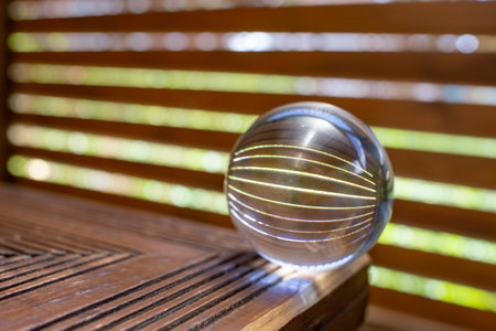 Optic distortion with a crystal globe, wooden boards fence, green grass and blue sky, abstractの写真素材