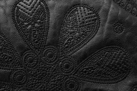 Soft focus close up detail of  thread embroidery design on black genuine leather, abstract  backdropの写真素材