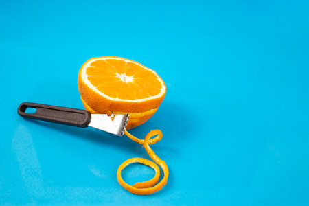 Citrus Zester and a half of an orange fruit on blue background, soft focusの写真素材