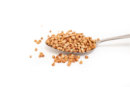 Buckwheat seeds pile in a stainless steel spoon isolated on whiteの写真素材