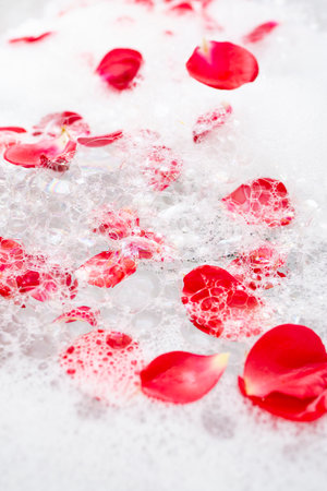 White bath foam with red roses petals floating, abstract bubbles texture
