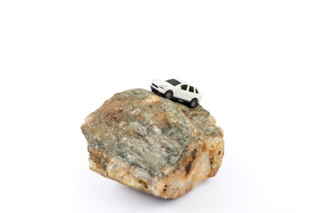Small generic suv model car climbing a rock in balance isolated on whiteの写真素材