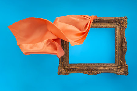 Orange satin fabric unveiling a empty baroque frame, on blue  backgroundの写真素材