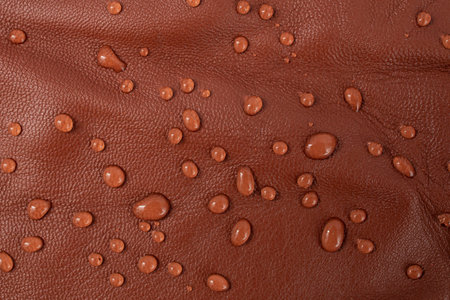 Round water drops on red brown leather texture, top view, soft focus close up abstractの写真素材