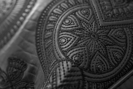 Soft focus close up detail of thread embroidery floral design on black genuine leather, abstract textured detailの写真素材