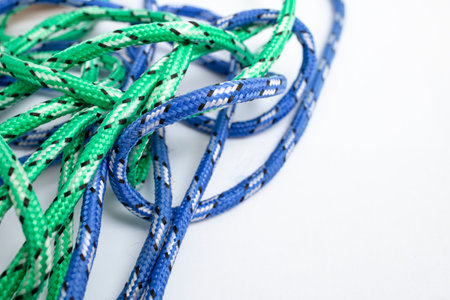 Tangled blue and green strings on white background with empty space