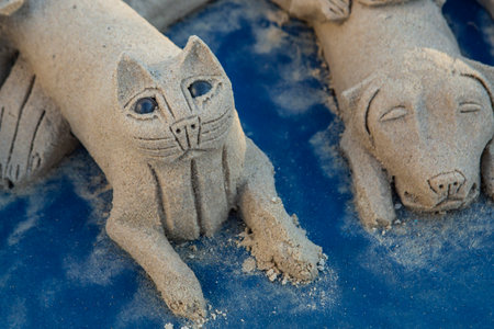 Cat and dog made of wet sand on a blue plastic backgroundの写真素材