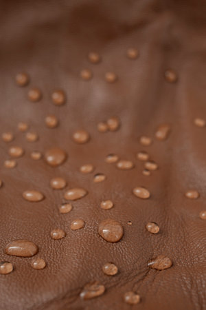 Water drops on red brown leather texture, top view, soft focus close up abstract pattern