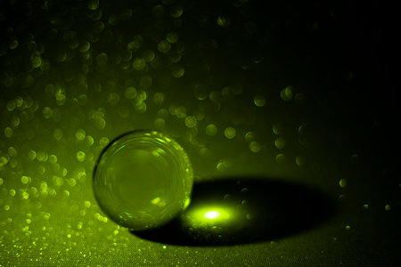 Green glitter reflections thru a lens ball, on dark green defocused  background, soft focusの写真素材