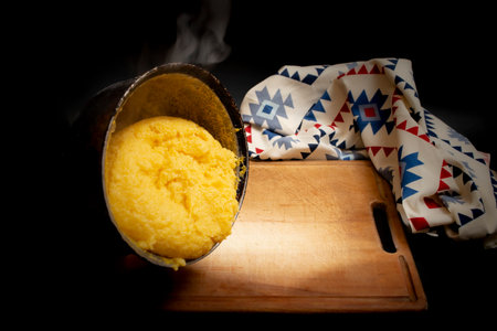 Romanian traditional mamaliga on a wooden chopping board next to a table cloth,