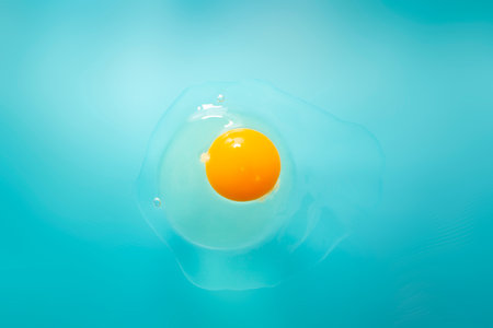 Raw cracked egg on blue background, soft focus close up, abstractの写真素材