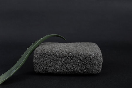 Black pumice stone with a aloe vera leaf, on dark gray background, abstract backdropの写真素材