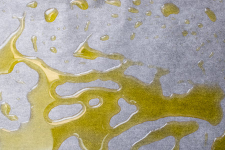 Extra virgin olive oil spread on a gray baking paper background, culinary   backdrop