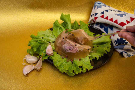 Romanian Christmas dish racituri,  kholodets, or kocsonya, on lettuce leaves, on golden glitter  backgroundの写真素材