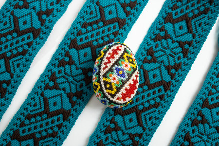 Beaded egg , easter decoration on blue textile border stripes background