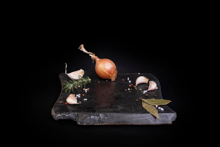 Charred cutting board with condiments and empty space for culinary product placement, side view  isolated on blackの写真素材