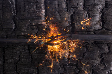 Sparks explosion between electrical cables, on burned wood texture background, fire hazard concept, soft focusの写真素材