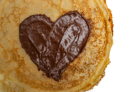 Heart shaped chocolate spread smudge on a golden pancake or crepe, close upの写真素材