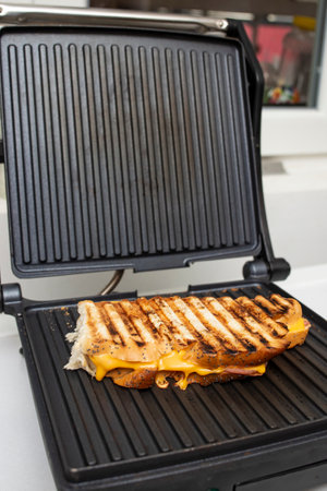 Sandwich with ham and melting cheese in a panini  machine grill , side viewの写真素材