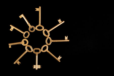 Multiple golden keys arranged as a round radial frame, on blackの写真素材
