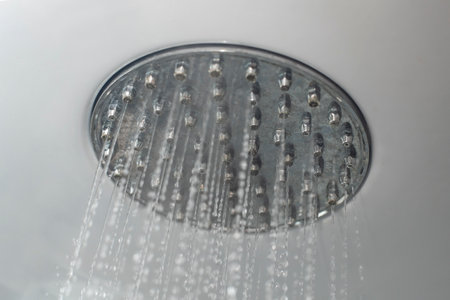 Shower head from a bathroom shower cabin ceiling with running hot water, soft focus close upの写真素材