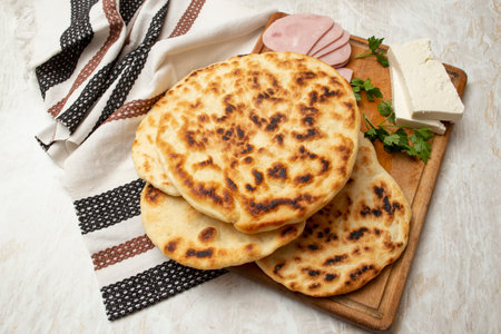 Fried pita bread stack on a wooden chopping board with goat cheese, homemade mealの写真素材