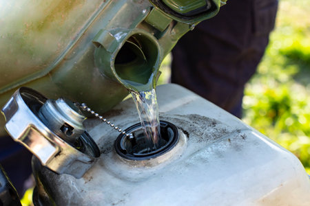 Filling a generator tank with gasoline fuel from a green metallic canister , soft focusの写真素材