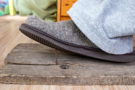 Sox covered foot stepping on a sharp rusty nail from a weathered wooden board, soft focusの写真素材