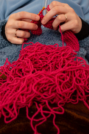 Woman hands knitting with a crochet hook and red thread , soft focusの写真素材