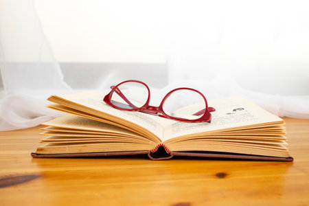 Hard cover book opened on a wooden desk with sunny window background, bible study  backdropの写真素材