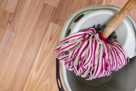 Used fabric rags pink mop in a gray bucket on wooden flooring , housekeeping minimal conceptの写真素材