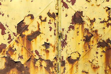 Flaky peeling yellow paint on brown metal rusty sheet with a x shape mark , abstract  backdrop