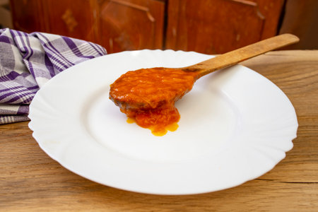 Orange color apricot jam in a full wooden spoon , on a white plate, soft focusの写真素材