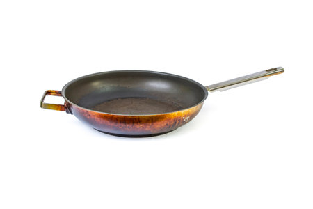 Empty overused frying pan with damaged coating isolated on white