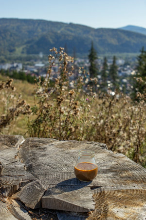 Coffee in a glass jar on a tree stump with mountain viewの写真素材