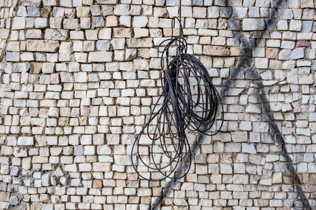 Tangled black electrical wire hanging on stone mosaic  decorationの写真素材