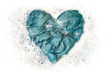 Soaking a blue fabric crumpled in the form of a heart ,on hot water with detergent foam for better stain removalの写真素材