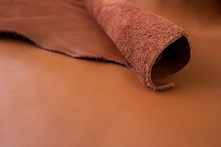 Red brown genuine leather swatches rolled , soft focus close up , abstract backdrop