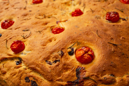 Oven baked focaccia bread with tomatoes and rosemary , side view soft focus close upの写真素材