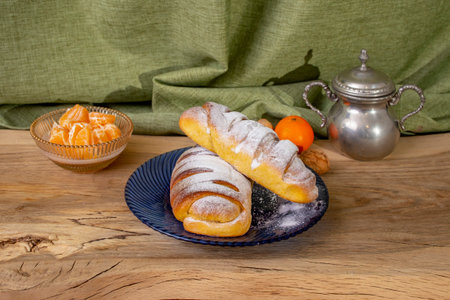 Sugar powdered jam buns on wooden oak table and a blue plate, soft focus