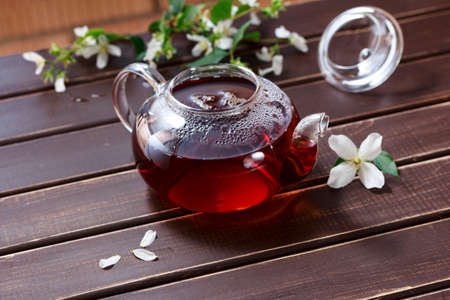 natural tea with Jasmine flowers in a teapot on a wooden table surfaceの写真素材