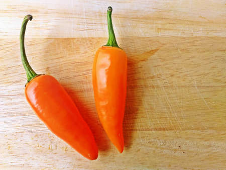 Orange chilli peppers on wooden cutting board