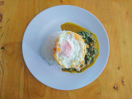 Rice with curry in coconut milk and over easy fried eggs on wooden backgroundの写真素材