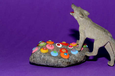 a dangerous gray wolf climbs a rock on a purple background