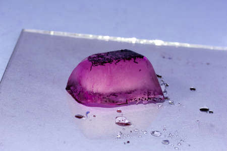 purple ice cube on glass on a blue backgroundの写真素材